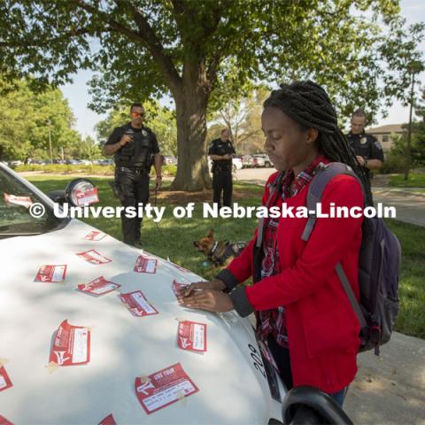 Elizabeth Uwase, a junior integrated science major from Rwanda, affixes her "Use Your Voice" pledge to a police car during the September 10 Cover the Cruiser event on East Campus. More than 75 students, faculty and staff made a pledge to stand up to sexual violence in the first day of the initiative. September 10, 2019.  Photo by Troy Fedderson / University Communication.